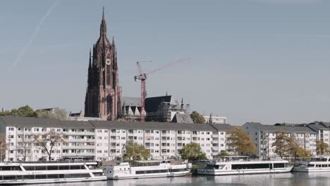landscape view of kaiserdom st. bartholomäus church, frankfurt with people walking at the park and eiseiner steg bridge as background