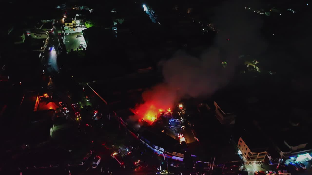 Drone shot circling an apartment fire with emergency vehicles and flashing lights