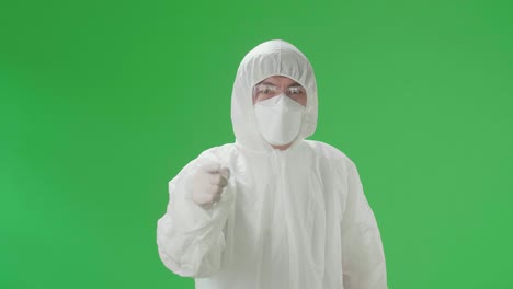 angry asian man wearing personal protective equipment uniform ppe, medical face mask and pointing displeased and frustrated to the camera in the green screen studio