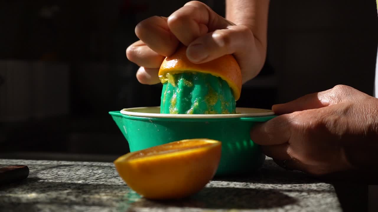 una mujer exprime jugo de naranja usando un exprimidor manual en la cocina, de cerca
