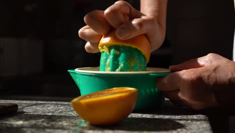 woman squeezes orange juice using a manual juicer in the kitchen - close up