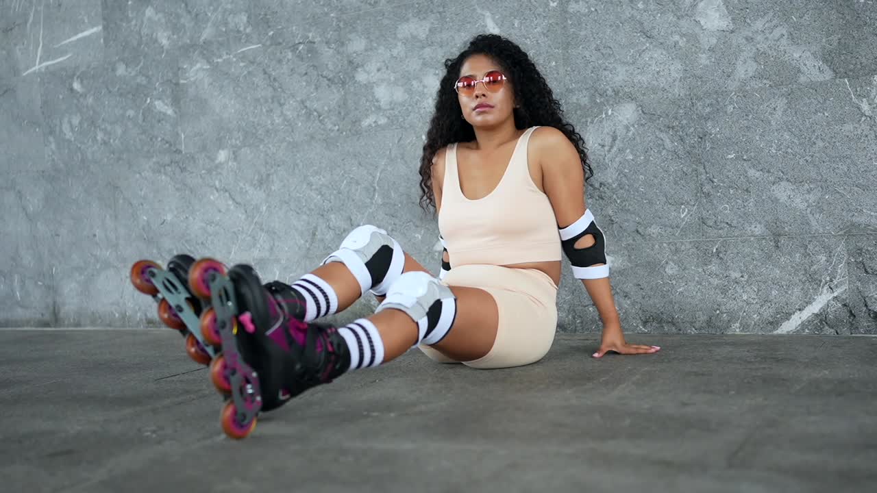 Woman in Roller Skates Sitting by Wall