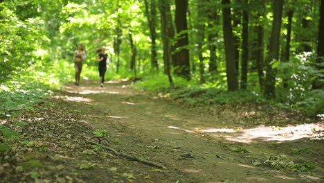 two sportswomen running in the woods