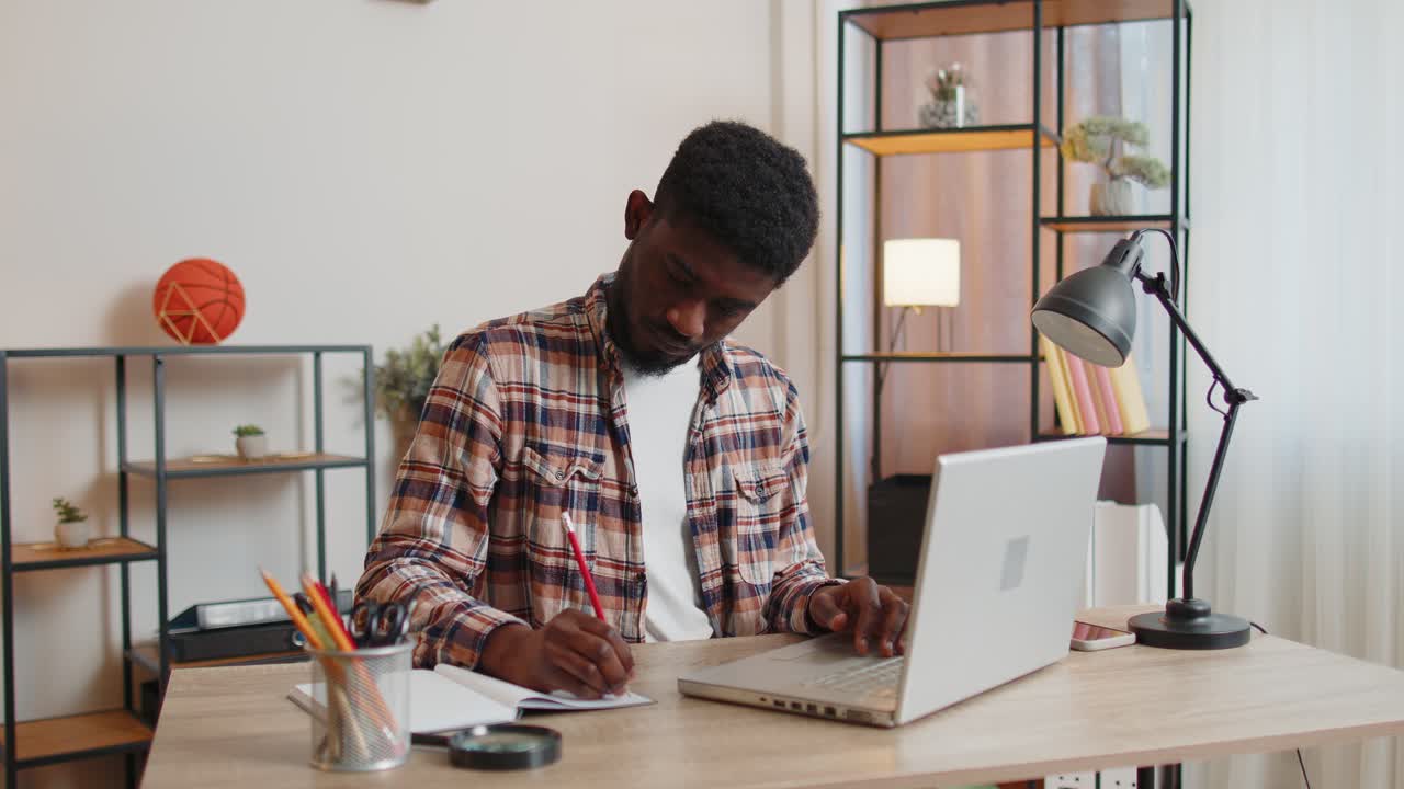 Young man guy using laptop computer sitting at table working online shopping from home office