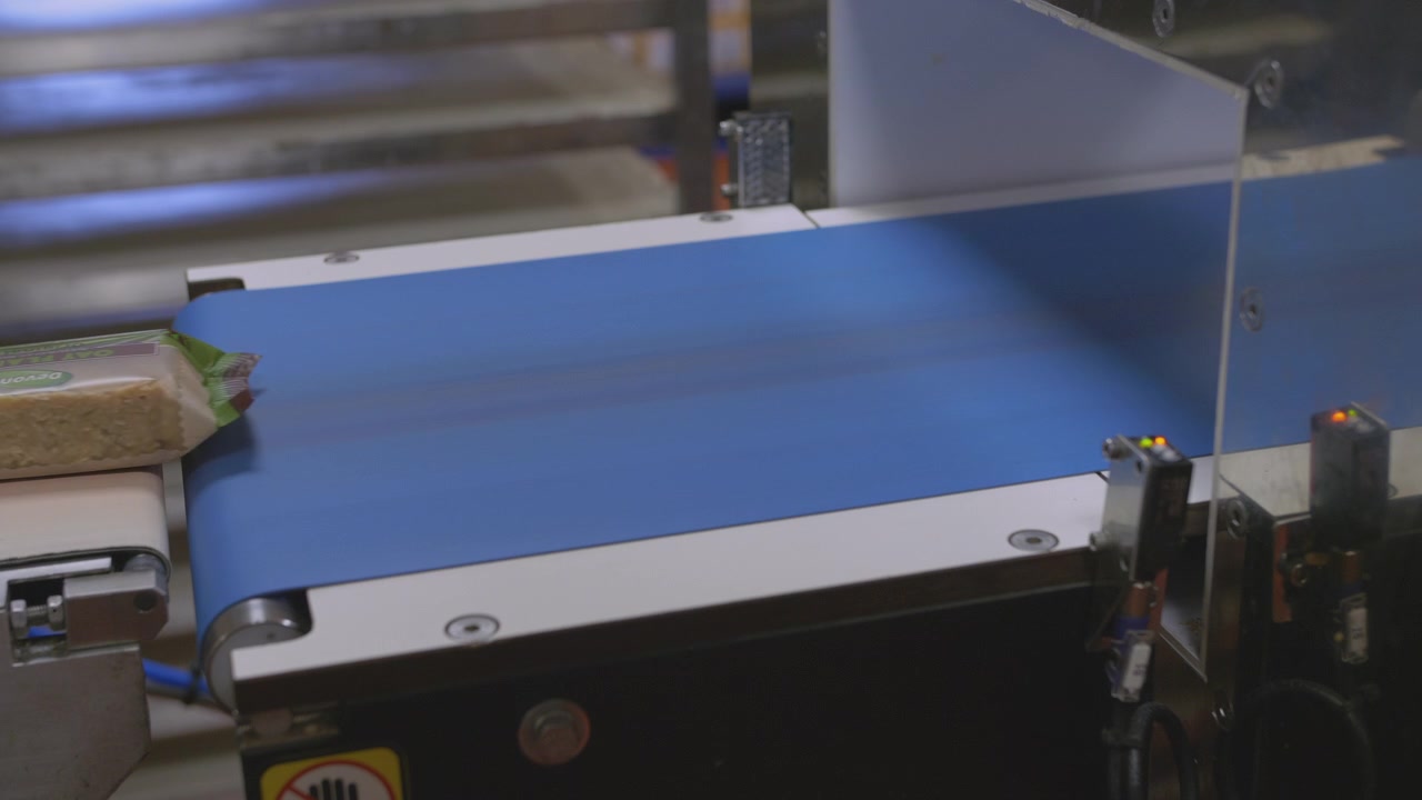 Barras de confeitaria movem-se rapidamente ao longo de uma esteira em uma linha de produção de fábrica