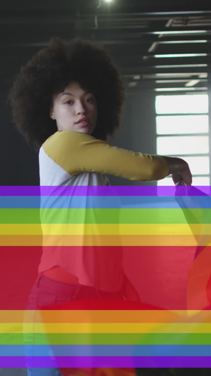 Animation of rainbow flag over african american woman waving with flag