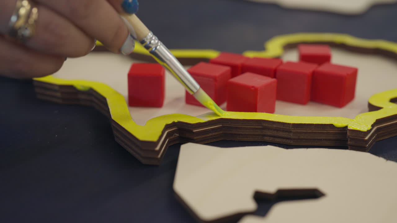 Careful Brushwork is Shown as Participant Paints Layered Wooden Pieces During a Painting Class - Close Up