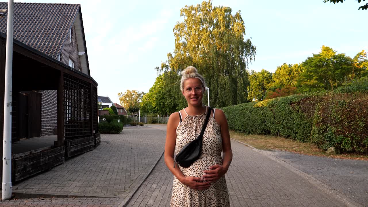 Slow motion shot of fashionable pregnant woman walking on path during golden hour, enjoying last calm moments alone