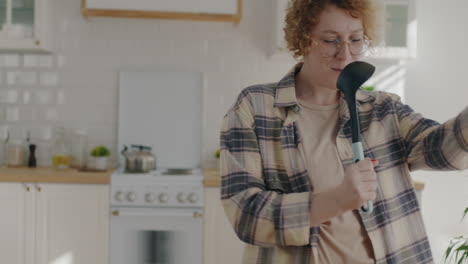 woman singing in kitchen with utensil microphone