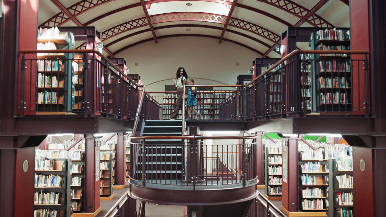 Woman and Young Girl Walking Down Staircase in Library