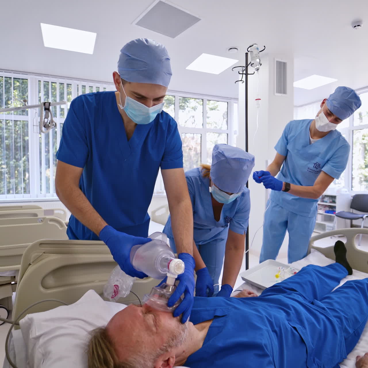 Male patient lying on bed and medical group of doctors helps him in the emergency room. Doctors and a nurse saving patient's life. Emergency concept.