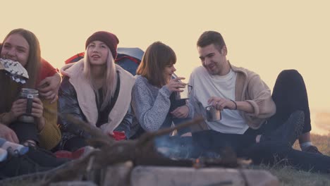 tourists drink tea at burning bonfire in evening slow motion