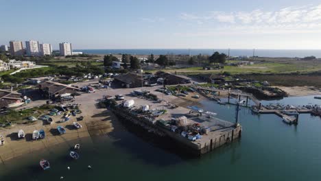 Pequeño-Puerto-Pesquero-En-Alvor-Portugal,-órbita-Aérea-Con-El-Horizonte-De-La-Ciudad