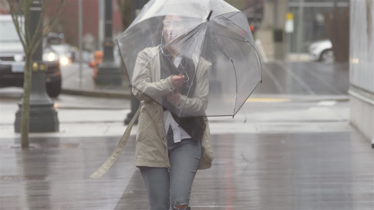 fotografía panorámica de una joven y hermosa mujer latina bailando con un paraguas en la ciudad mientras escucha música