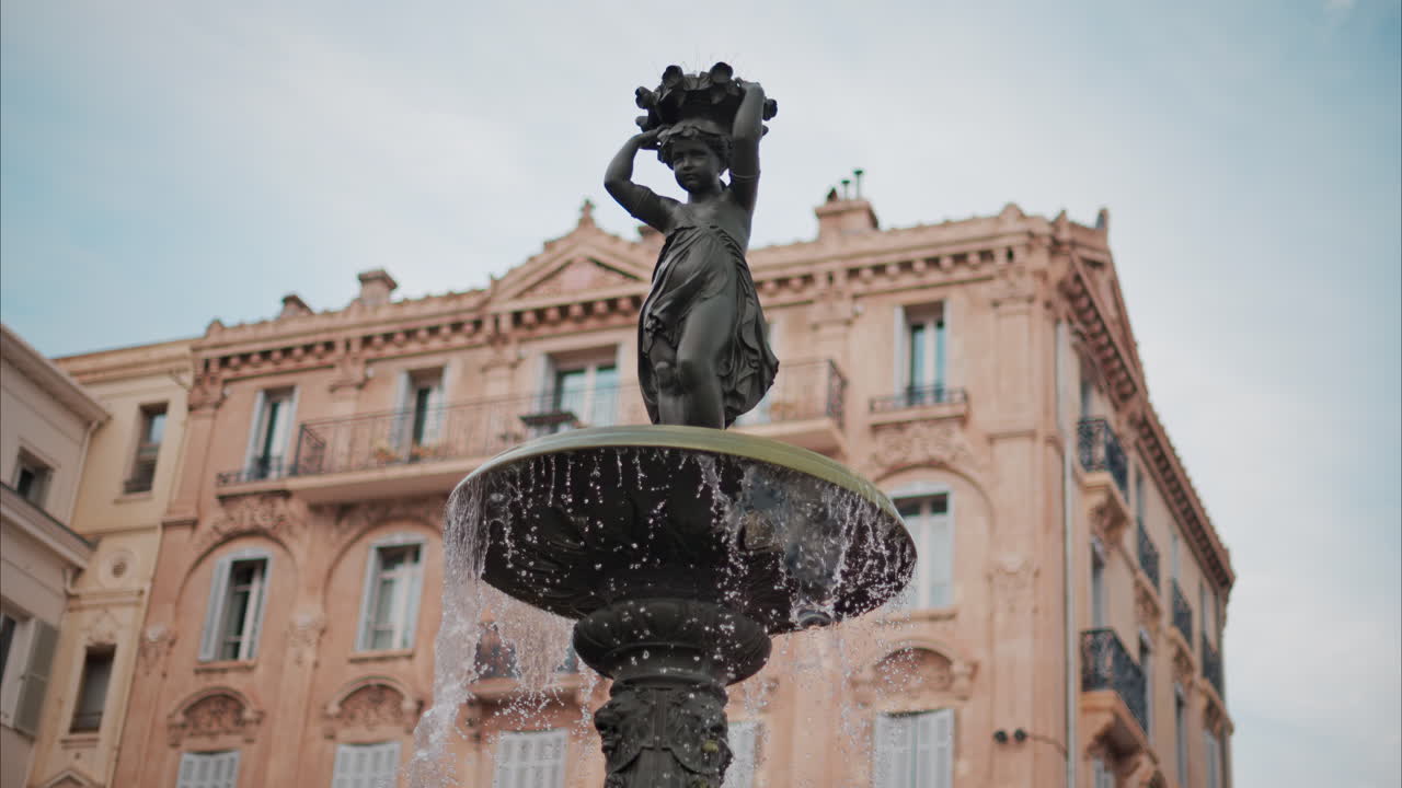 Water pouring in a fountain with a background of Cannes, France