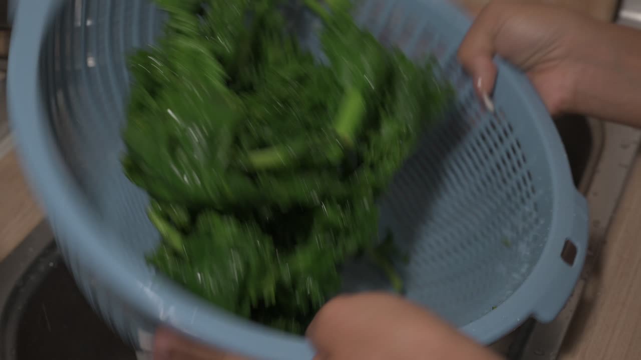 Young woman hands tossing and cleaning healthy green kale at home kitchen