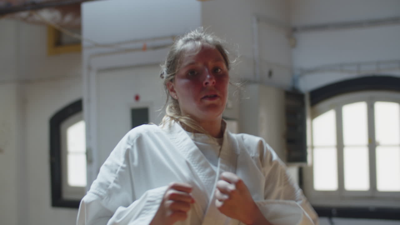 съемка с рук сфокусированного каратеки, выполняющего прыжки ногами на камеру