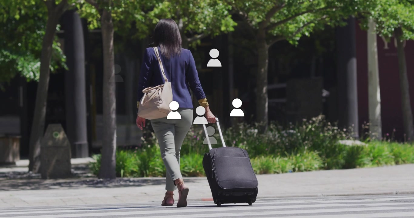 Reaching crosswalk, businesswoman pulling suitcase and tote bag, crossing toward office entrance