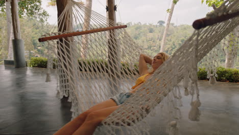 happy woman in hammock swaying peacefully on lazy summer day enjoying vacation lifestyle at holiday resort