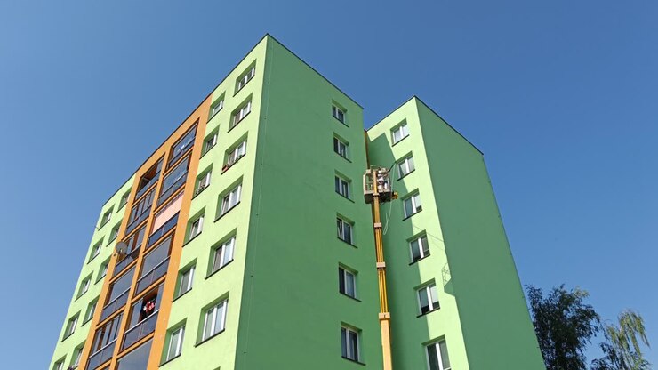 Operaio irriconoscibile che pulisce la facciata della casa prefabbricata costruita in epoca comunista e recentemente ristrutturata