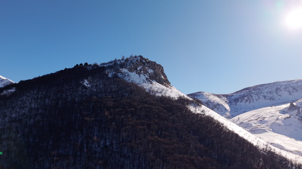 Vista aerea del ripido versante alpino italiano innevato con orizzonte soleggiato blu