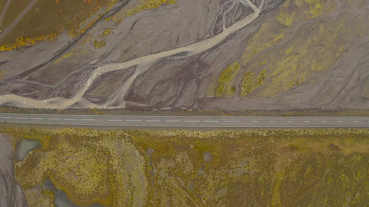 Sliding aerial drone shot, top view of road, Iceland. Path across the river.