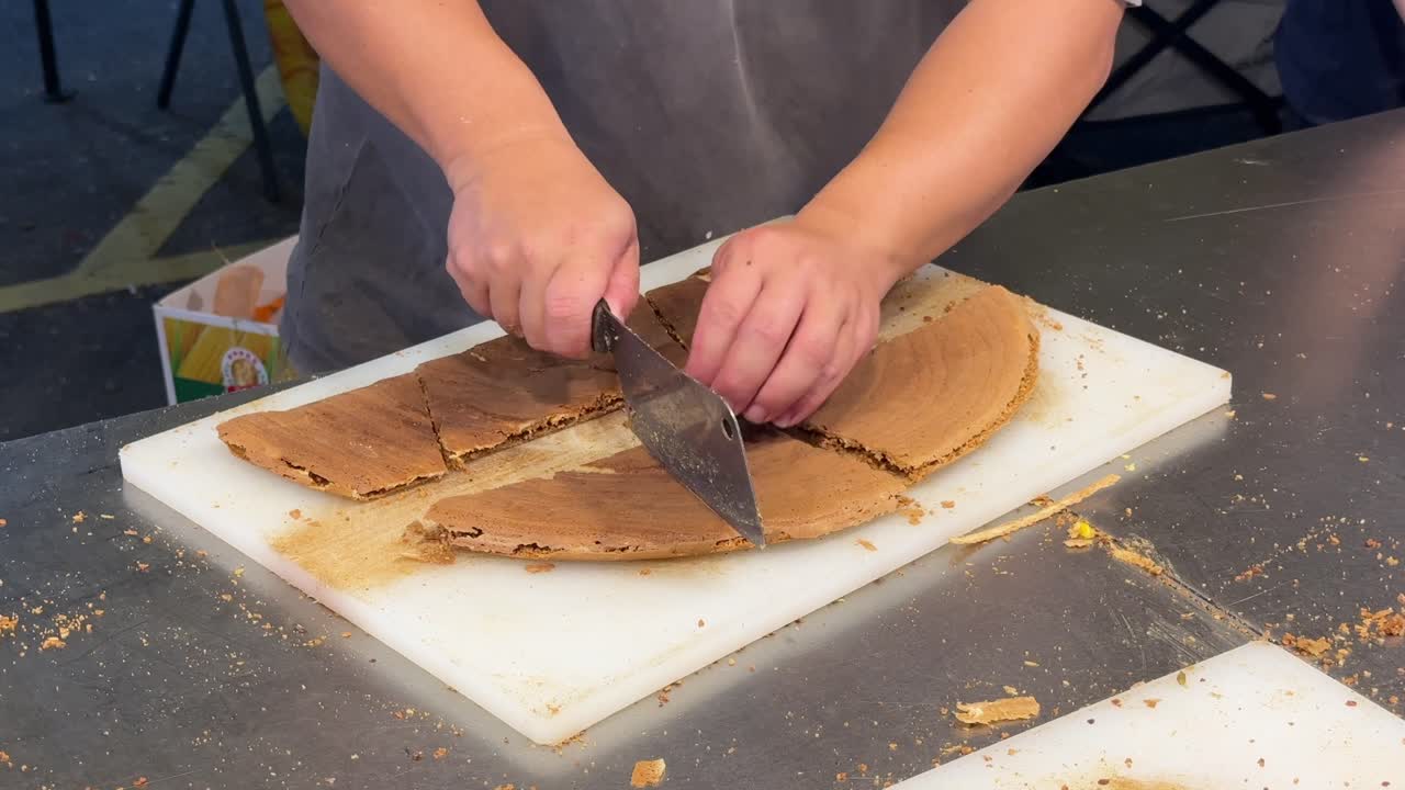 A close-up of a vendor cutting up large peanut pancakes, aka apam balik, on a hawker street food stall at a pasar malam in SS2, Petaling Jaya, Malaysia