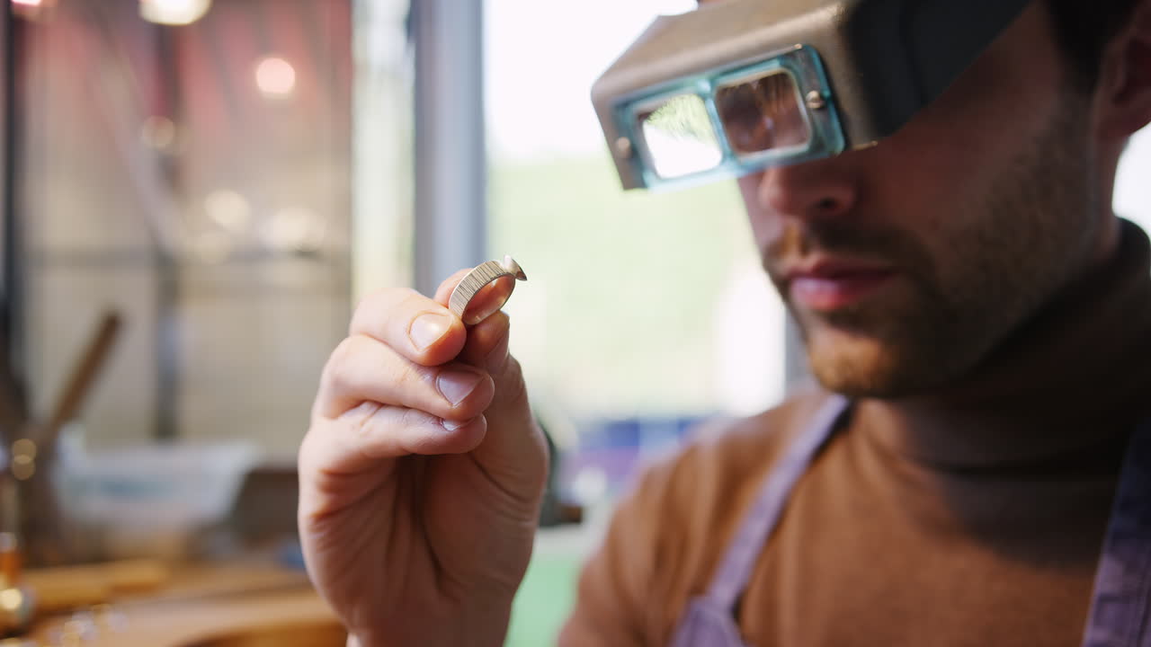 close up de un joyero masculino mirando el anillo a través de las lupas de la banda de la cabeza en el estudio