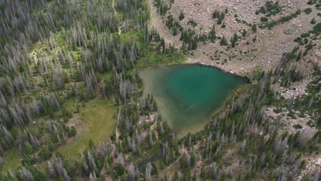 aerial view of clear green alpine amethyst lake, valley of uinta mountains range utah usa, pull back drone shot