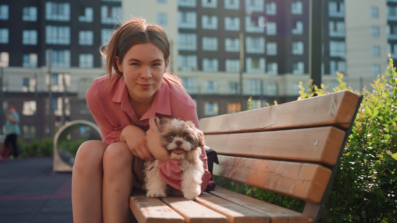 Caucasian Woman Gently Embraces Her Dog Outdoors, Woman Sitting On Bench Sharing Tender Moment With Her Pet Dog, Young Woman With Light Skin Affectionately Holding Her Dog In Warm Sunlight Outdoors