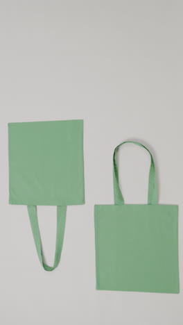 vertical video of green bags on grey background, copy space, slow motion