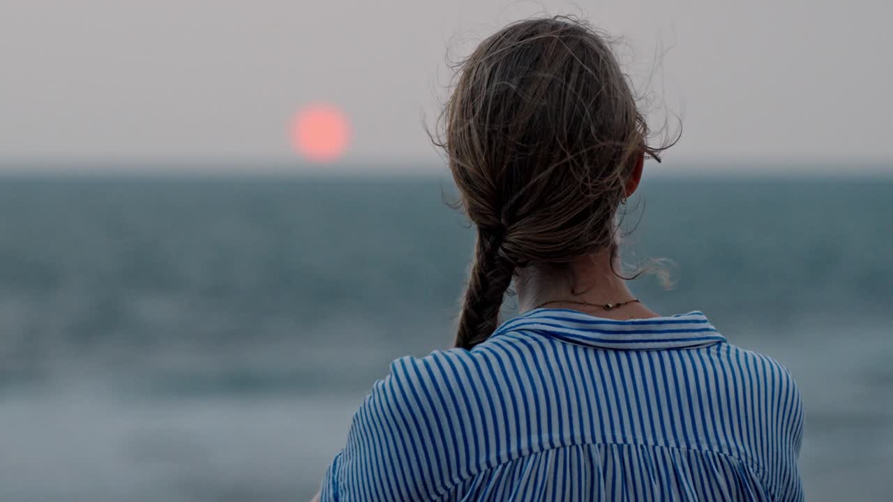 Klidný okamžik v Galle na Srí Lance, kdy žena zírá na širý oceán během dechberoucího západu slunce.