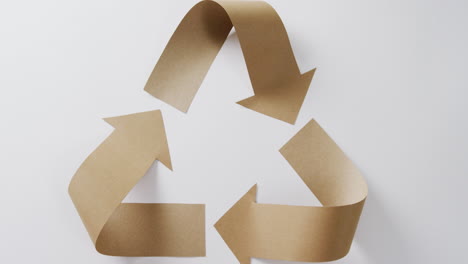 primer plano del símbolo de reciclaje de las flechas de papel sobre fondo blanco.