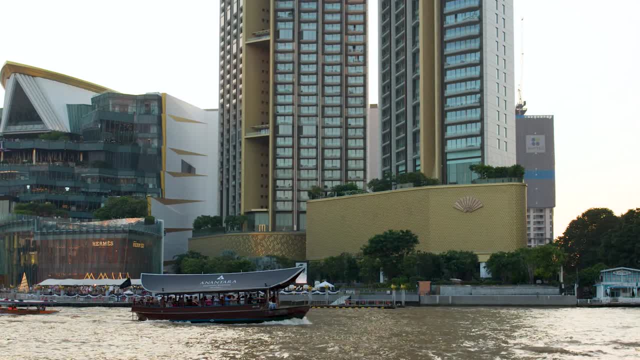 Một chiếc phà gỗ truyền thống lướt trên sông với phông nền là những tòa nhà chọc trời hiện đại