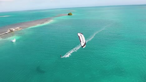 Hombre-De-Vista-Aérea-Se-Divierte-Usando-Cometa-De-Núcleo-Blanco-En-El-Mar-Caribe-Turquesa,-Los-Roques