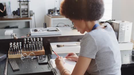 trabajadora biracial dibujando el diseño de joyas en el taller en cámara lenta