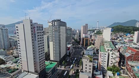 aerial view of busan city skyline downtown, cars traffic on jungang-daero road with skyscraper buildings architecture, view of diamond tower and mountains - wide high angle view