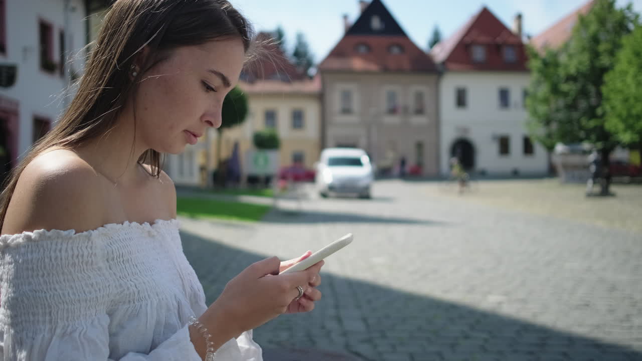 유럽 마을에서 스마트폰을 사용하는 젊은 여성