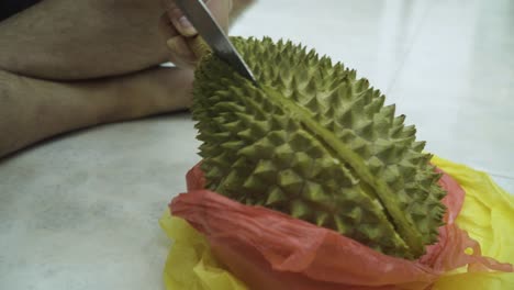 hands of man cutting the mao shan wang durian using a sharp knife - close up