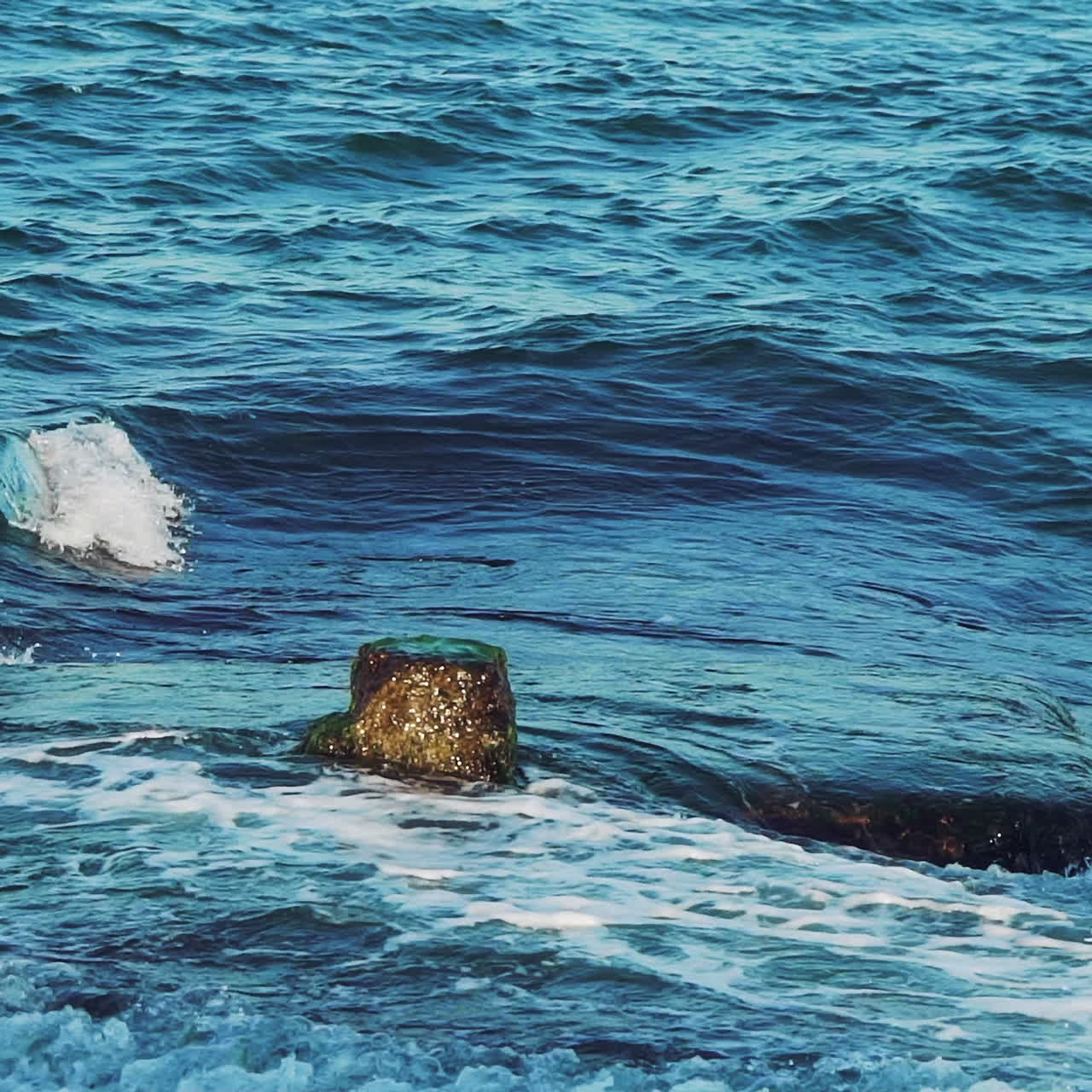 Sea. Splashes of the wave scatter from the impact of the breakwater. Slow motion.