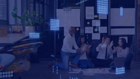Data processing animation over diverse team collaborating on floor in modern office