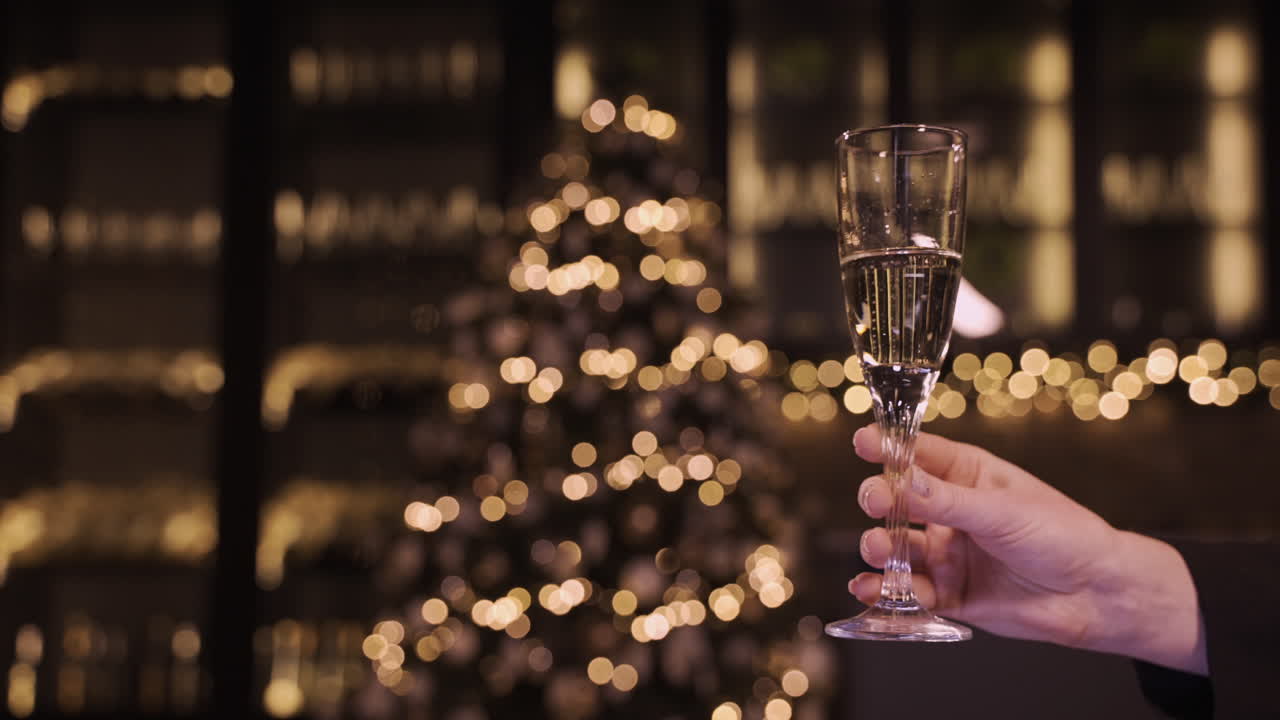 Camera Focuses On The Hand Of A Woman Holding A Glass Of Champagne At The New Year's Party 1