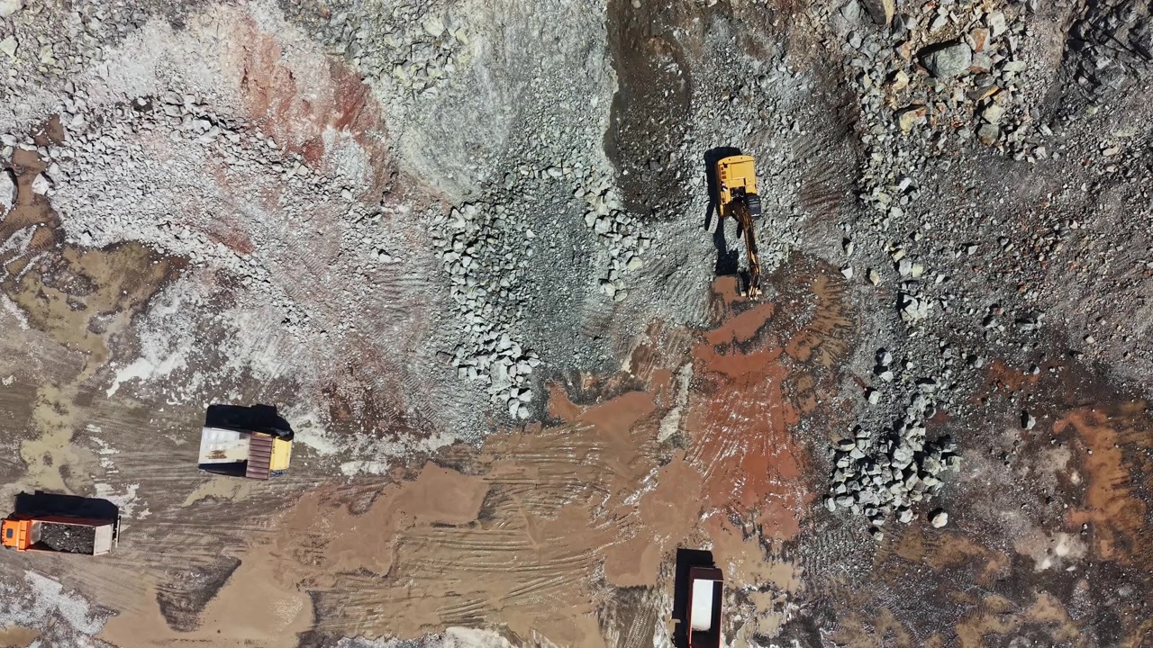 Granite quarry site with machinery working on stone extraction and trucks transporting materials in an active operation area