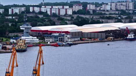 industrial docks with tugboats, warehouses, and scrap piles near residential buildings in riga