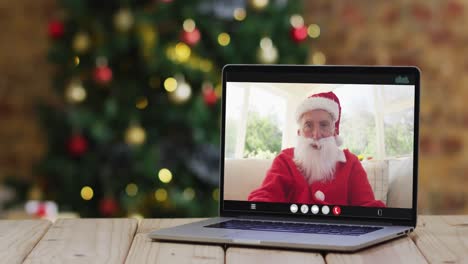 Älterer-Kaukasischer-Mann-Im-Weihnachtsmannkostüm-Bei-Videoanruf-Auf-Laptop,-Mit-Weihnachtsdekorationen-Und-Baum