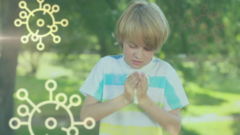 animation of macro covid-19 cells icons floating over caucasian boy sneezing