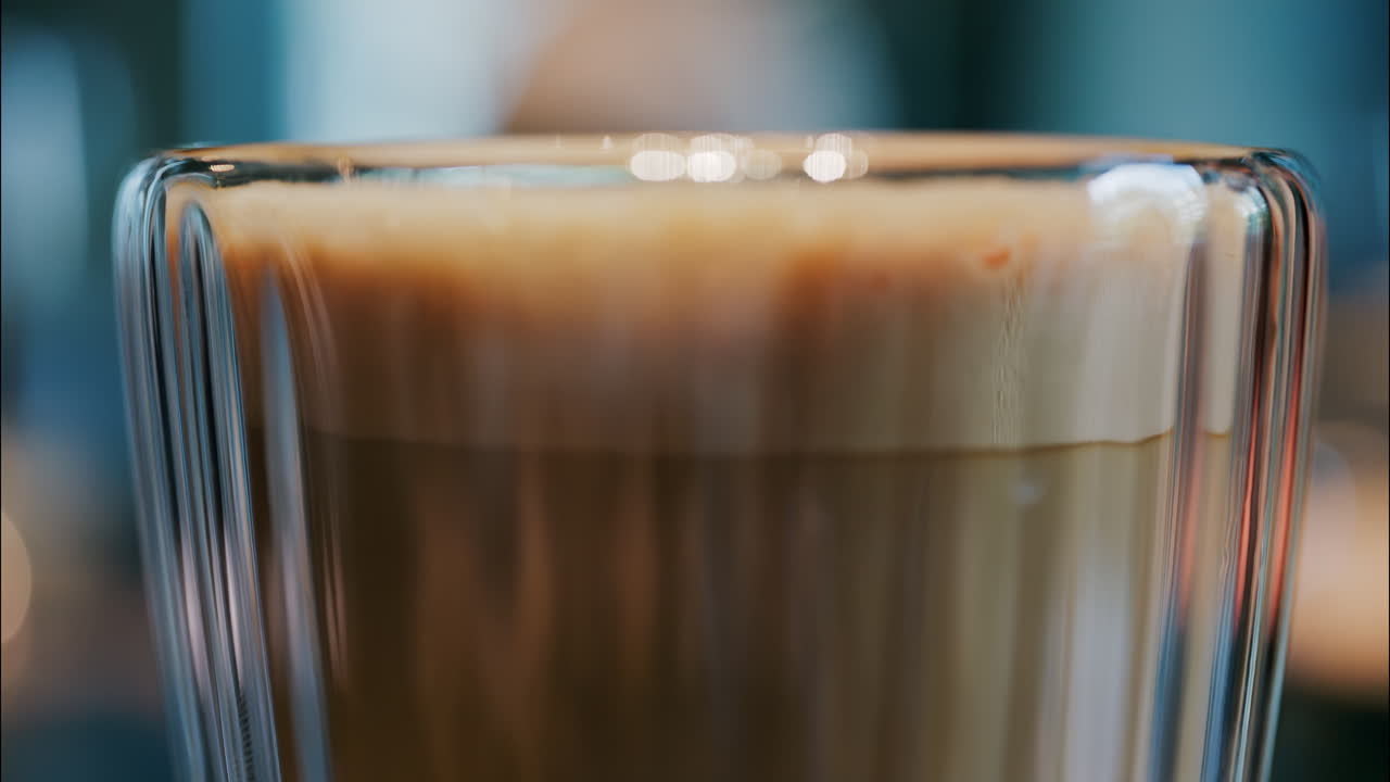 Close up of a glass cup with a latte at a cafe