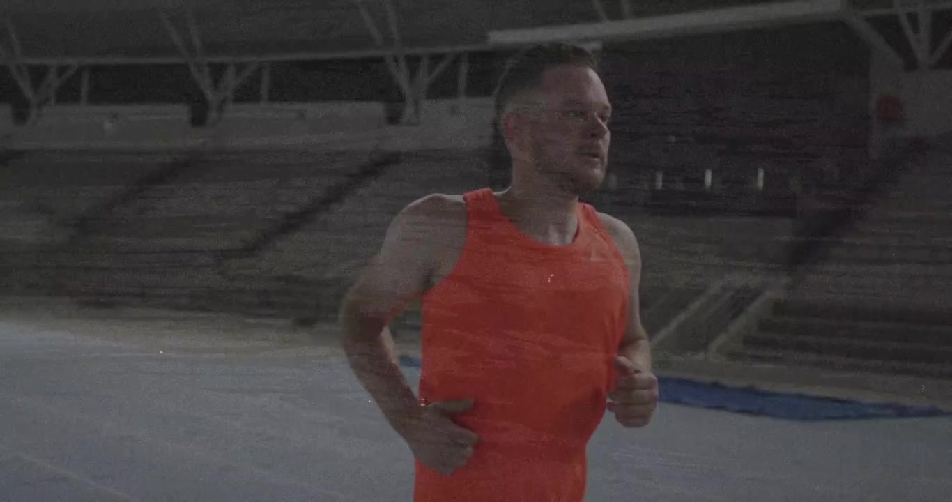 Mężczyzna sportowiec uderzający w bieżnię protezą ostrzową, poruszający się naprzód w stałym tempie podczas treningu sportowego.