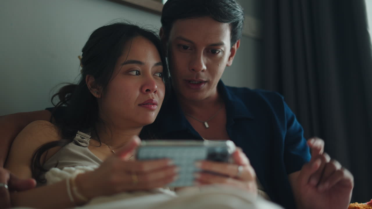 Couple Watching Phone in Bed