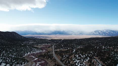 High-elevation-drone-view-of-a-remote-highway-in-the-rocky-mountains-with-snow